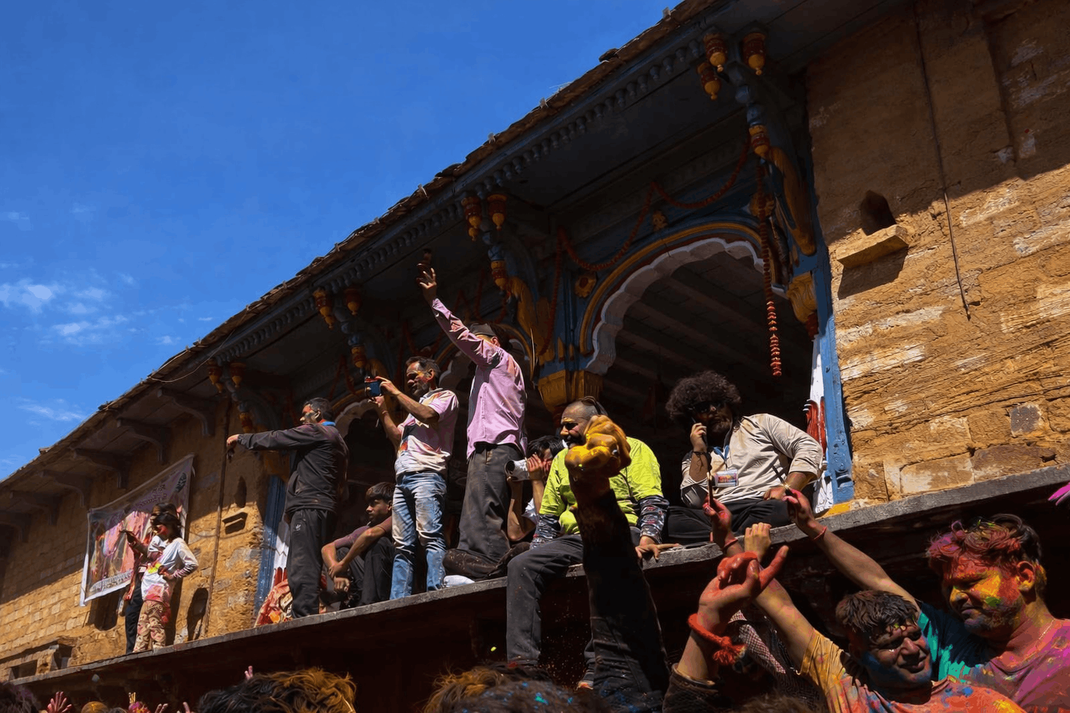 Families and travelers playing Holi in Gopeshwar surrounded by Himalayan mountain views